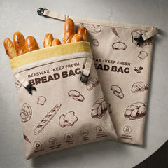 Two beige linen bread bags laid flat on a light gray textured tabletop