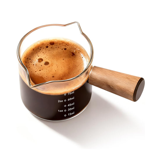 Glass espresso measuring cup with wooden handle filled with espresso