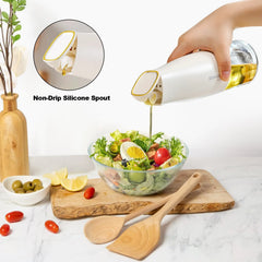 Hand pouring oil over a fresh salad using a white oil dispenser pourer