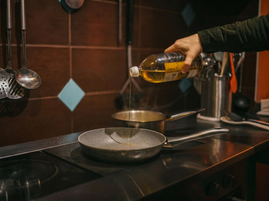 Cooking oil being poured from a leaking bottle into a frying pan, showing messy kitchen oil control during everyday cooking