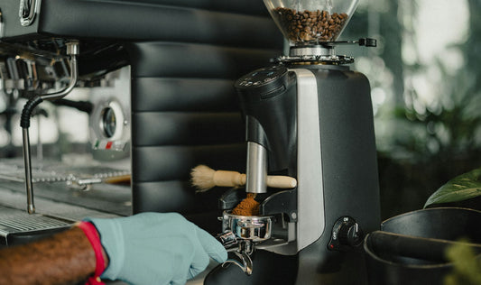 Barista preparing espresso with a coffee grinder and espresso machine