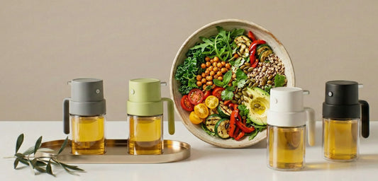 Glass oil sprayer bottles displayed beside a healthy low-calorie salad bowl for controlled oil cooking