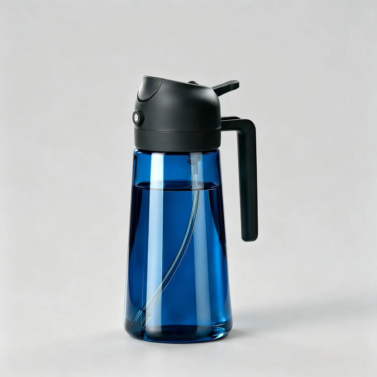 Blue glass oil dispenser bottle with black lid and handle for kitchen cooking on light grey background