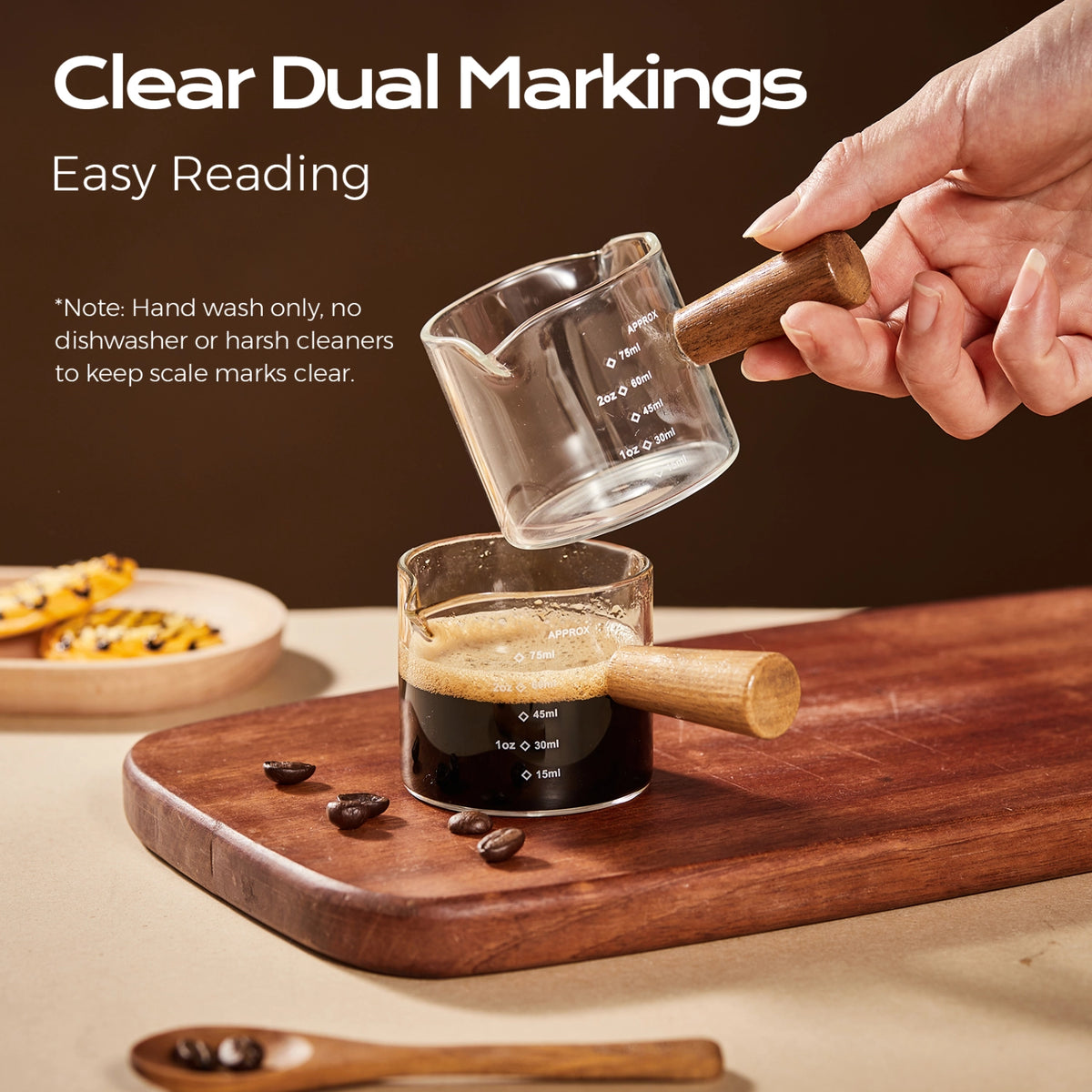 Wooden-handle glass espresso measuring cups showing milliliter and ounce markings.