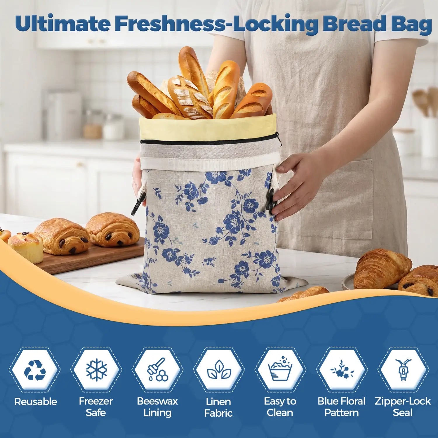 A person is holding a reusable bread bag with a blue floral pattern, filled with various types of bread, including baguettes and croissants. The bag features a zipper closure and is displayed on a kitchen counter surrounded by baked goods.#Blue