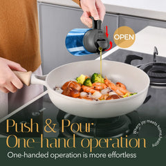 Blue glass cooking oil dispenser bottle with black lid pouring olive oil into a wok with seafood and vegetables