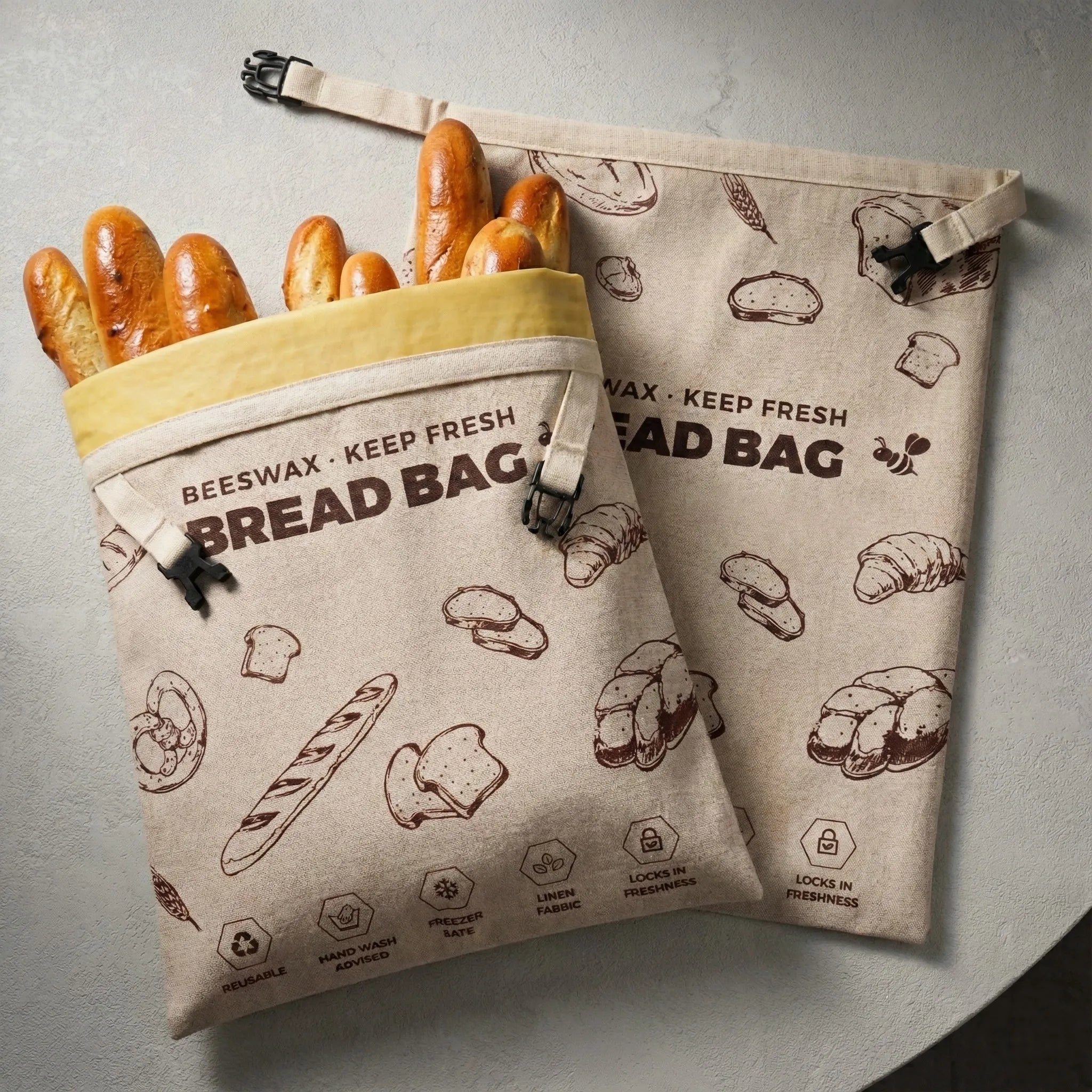 Two beige linen bread bags laid flat on a light gray textured tabletop