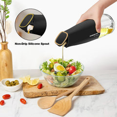 Hand pouring oil over a fresh salad using a black oil dispenser pourer