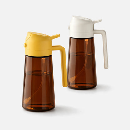 Two dark brown glass oil sprayers with white and orange spray heads.