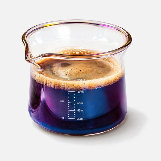 Iridescent glass espresso measuring cup with pouring spouts and scale markings.