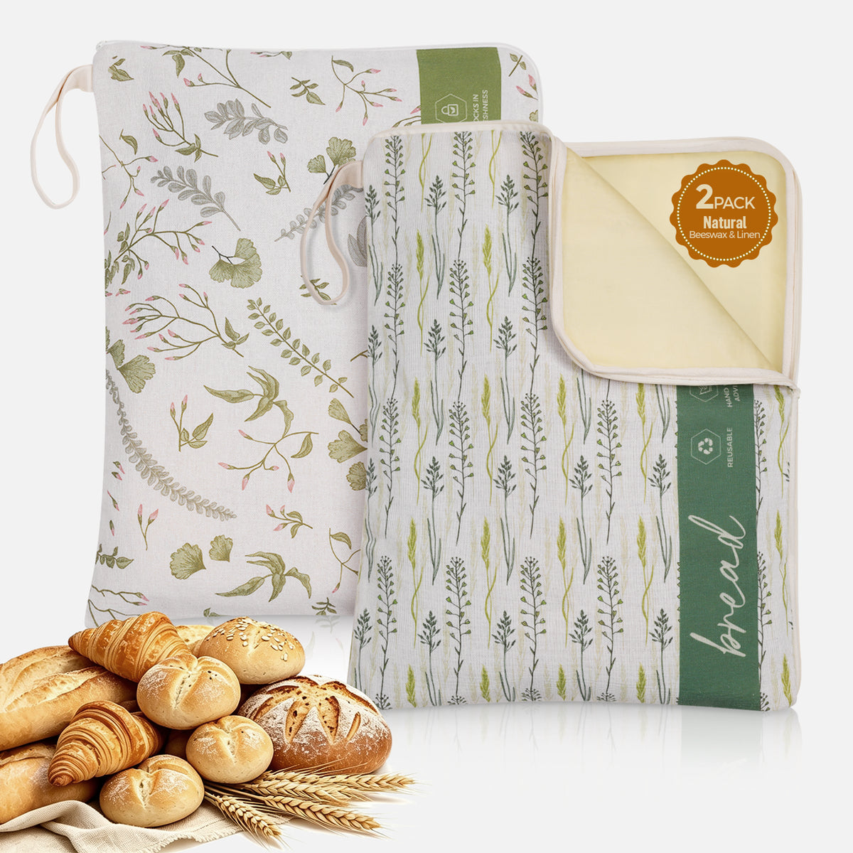 Two botanical-print L-shaped zipper beeswax bread bags, one open to show the lining, with bread at the lower left.