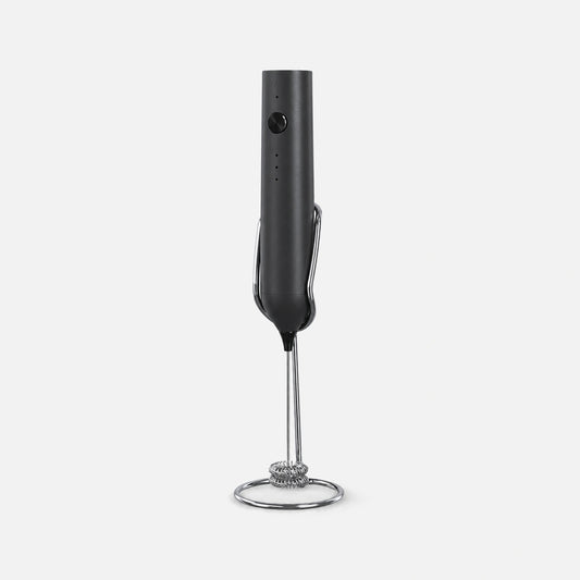 Black rechargeable milk frother with a stand.