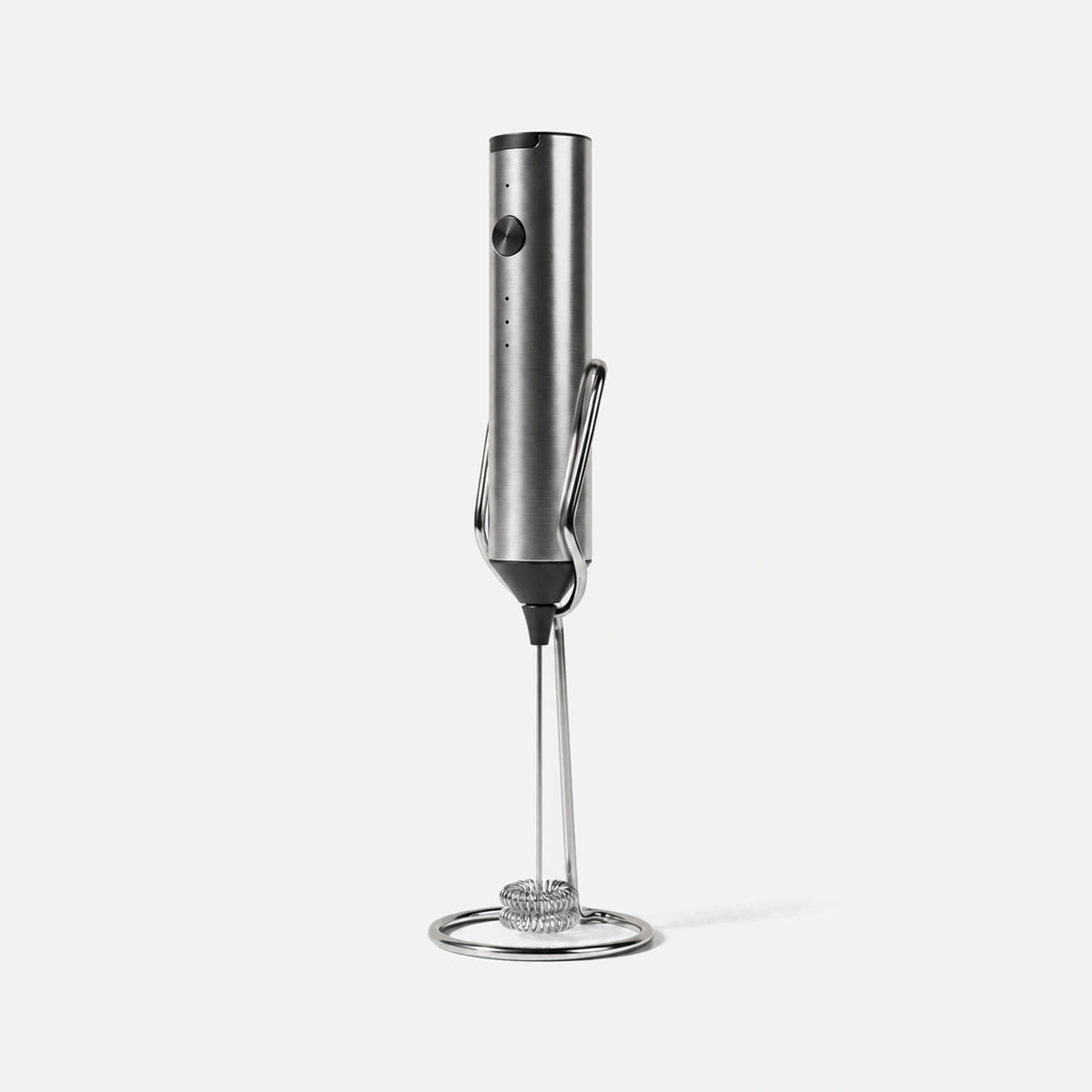Silver rechargeable milk frother with a stand.