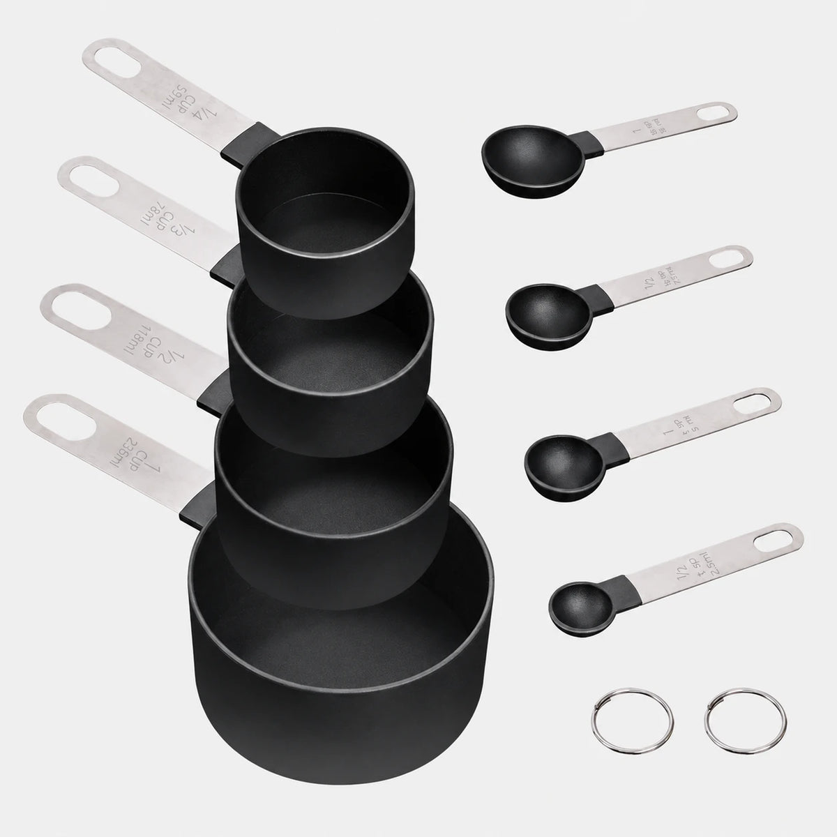 Eight black measuring cups and spoons with metal handles and two storage rings on a light gray background