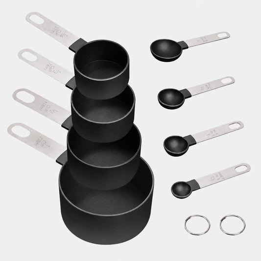 Eight black measuring cups and spoons with metal handles and two storage rings on a light gray background