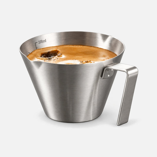 Stainless steel espresso shot cup in silver, with a handle and pouring spout.